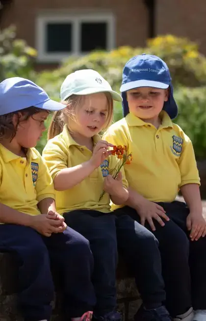 Three Pocklington Pre-School pupils looking at a flower